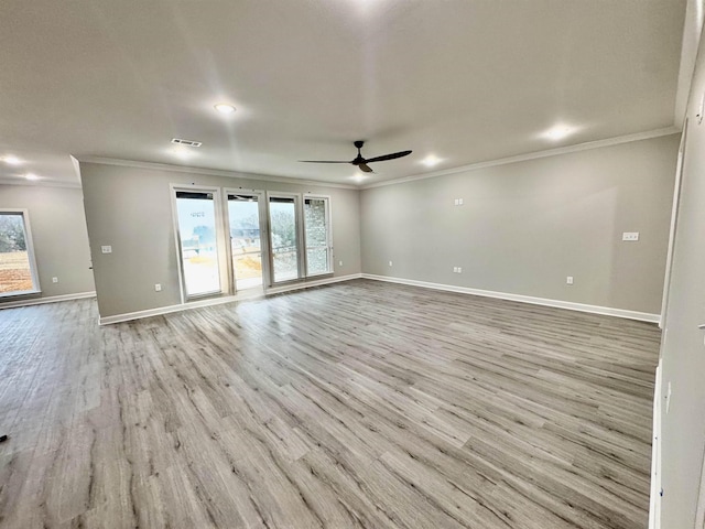 unfurnished room with light wood finished floors, visible vents, a ceiling fan, ornamental molding, and baseboards