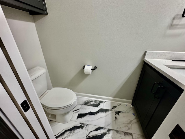 half bath with marble finish floor, vanity, toilet, and baseboards