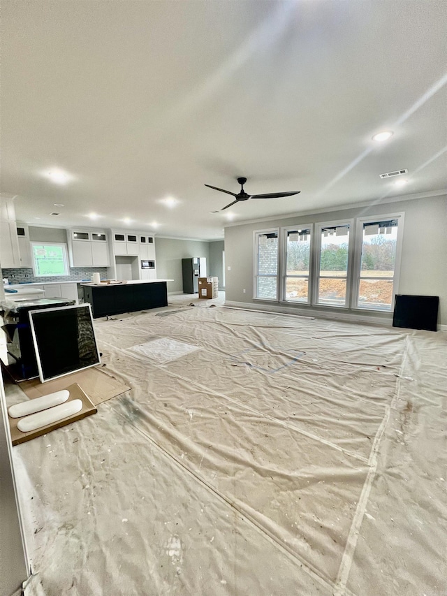 unfurnished living room with baseboards, visible vents, and ceiling fan