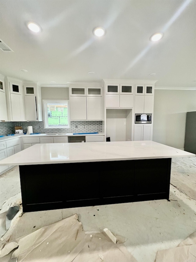 kitchen featuring a kitchen island, stainless steel microwave, and white cabinetry