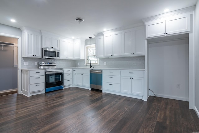 kitchen with dark hardwood / wood-style flooring, backsplash, stainless steel appliances, decorative light fixtures, and white cabinets