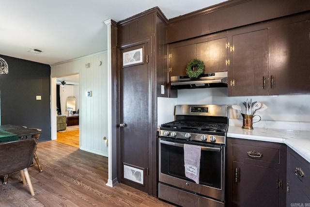 kitchen with ornamental molding, dark brown cabinetry, extractor fan, hardwood / wood-style flooring, and stainless steel gas stove