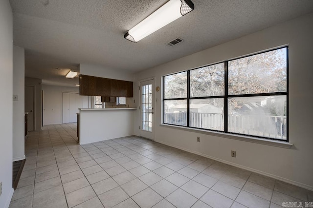 kitchen featuring a textured ceiling, light tile patterned floors, and kitchen peninsula