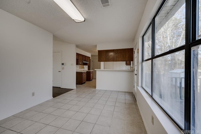 spare room with a healthy amount of sunlight, light tile patterned floors, and a textured ceiling