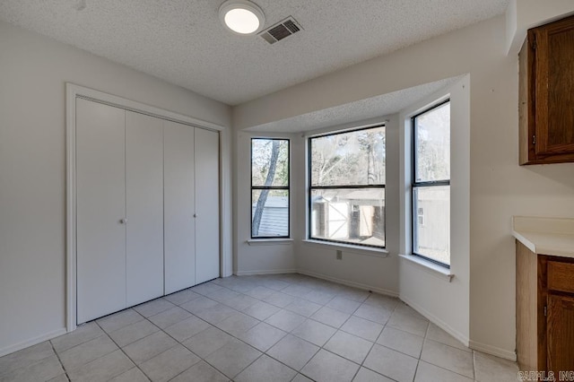 unfurnished bedroom featuring a closet, light tile patterned floors, and a textured ceiling