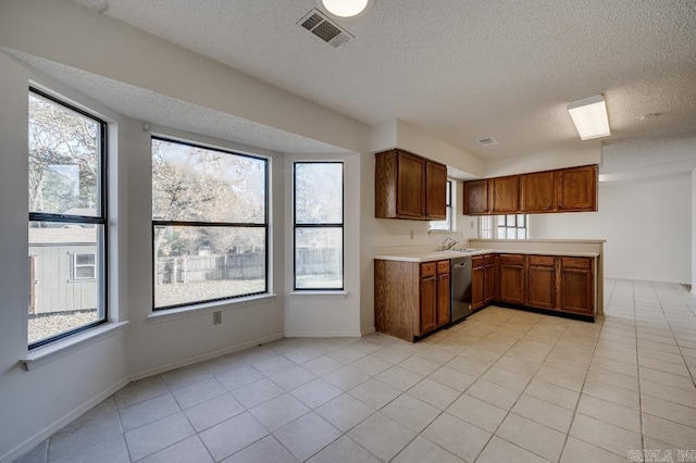 kitchen featuring dishwasher, light tile patterned flooring, and a textured ceiling