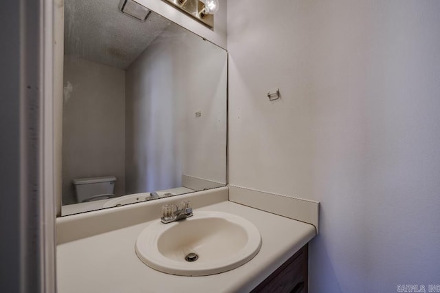 bathroom featuring vanity, a textured ceiling, and toilet