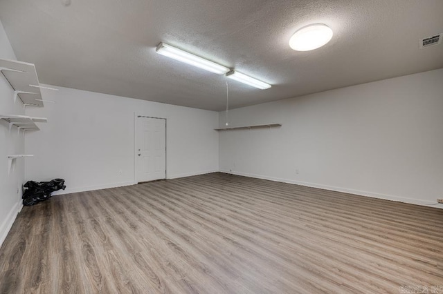 spare room featuring light wood-type flooring and a textured ceiling