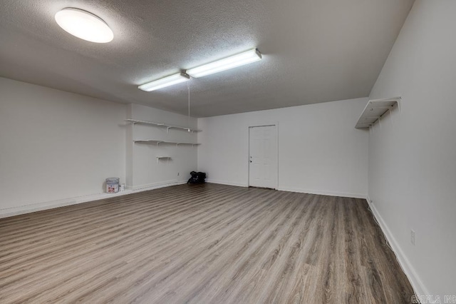 basement featuring wood-type flooring and a textured ceiling