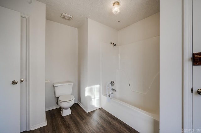 bathroom with shower / bath combination, a textured ceiling, hardwood / wood-style flooring, and toilet