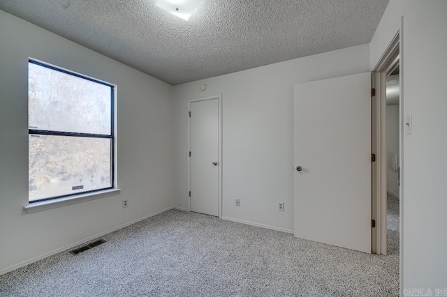 unfurnished bedroom with light colored carpet and a textured ceiling