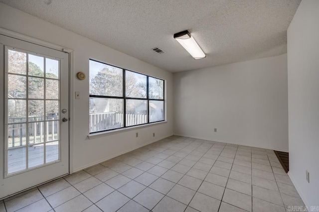 spare room featuring light tile patterned flooring and a textured ceiling