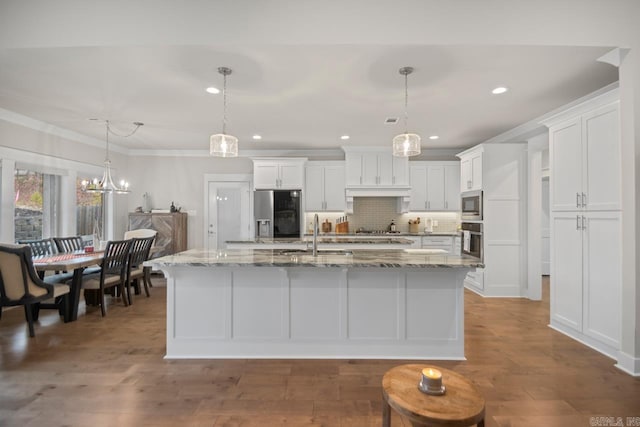 kitchen featuring white cabinetry, sink, pendant lighting, a kitchen island with sink, and appliances with stainless steel finishes