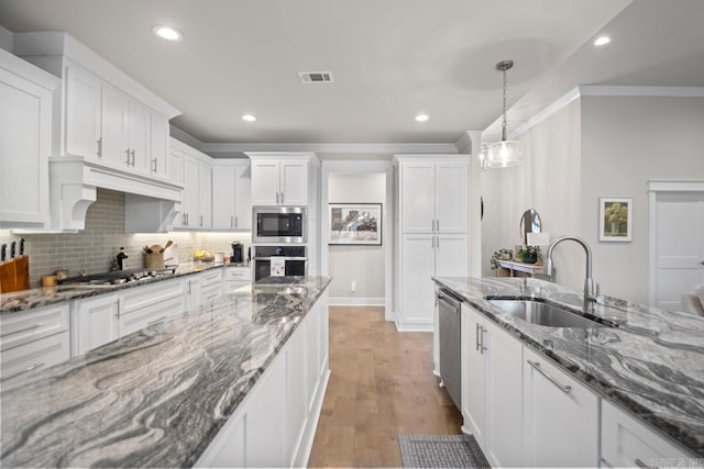 kitchen with pendant lighting, white cabinets, sink, dark stone countertops, and appliances with stainless steel finishes