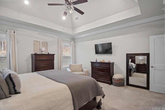 bedroom with a raised ceiling, light colored carpet, high vaulted ceiling, and ceiling fan