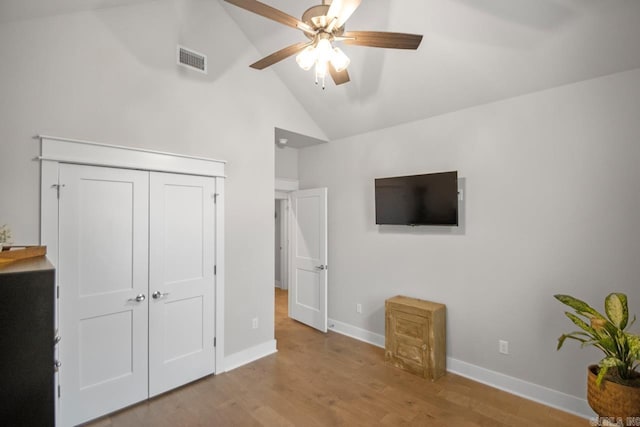 unfurnished bedroom with ceiling fan, a closet, light hardwood / wood-style floors, and vaulted ceiling