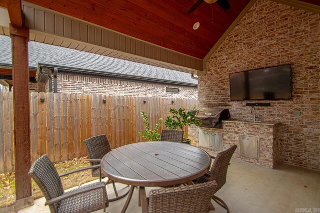 view of patio with an outdoor kitchen, ceiling fan, and a grill