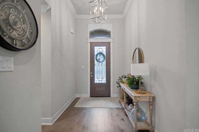 foyer entrance with hardwood / wood-style floors, an inviting chandelier, and ornamental molding