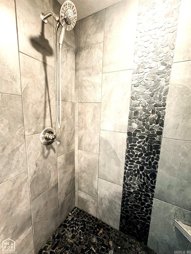 interior details with a tile shower and a textured ceiling