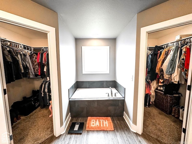 bathroom with hardwood / wood-style flooring and tiled tub