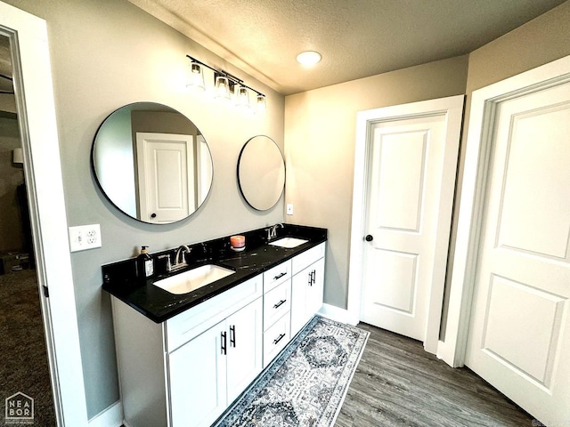 bathroom with hardwood / wood-style floors, vanity, and a textured ceiling