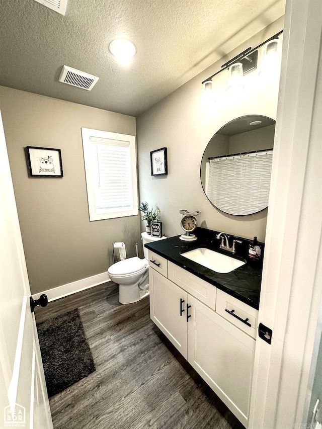 bathroom featuring hardwood / wood-style flooring, vanity, toilet, and a textured ceiling