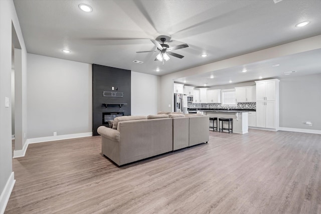 108 Delle Ln, Brookland, AR 72417 - living room featuring light wood finished floors, ceiling fan, baseboards, and a fireplace