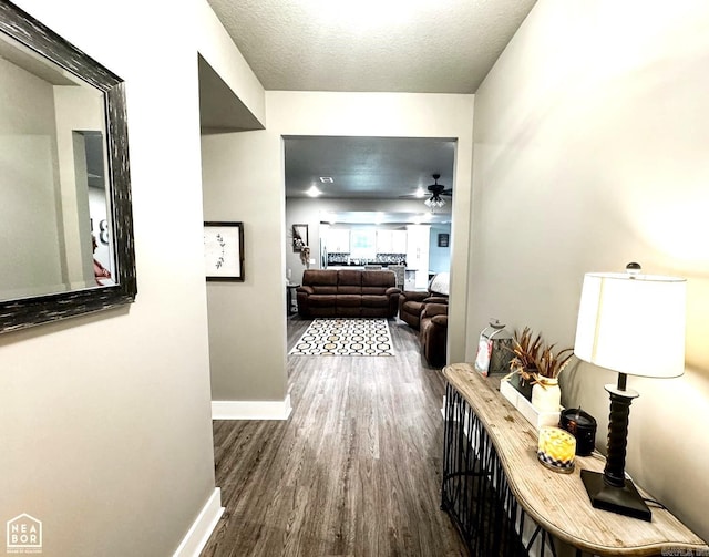 corridor with dark hardwood / wood-style floors and a textured ceiling