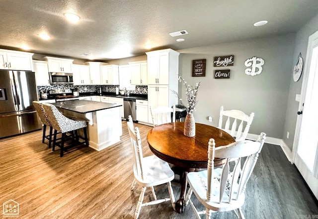 dining space with wood-type flooring, a textured ceiling, and sink