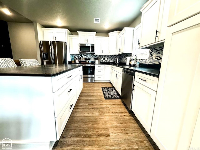 kitchen featuring sink, stainless steel appliances, light hardwood / wood-style floors, decorative backsplash, and white cabinets