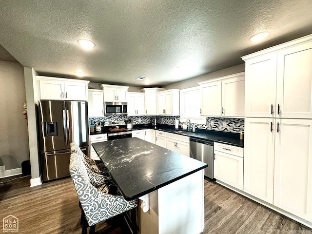 kitchen featuring white cabinets, a kitchen breakfast bar, sink, appliances with stainless steel finishes, and a kitchen island