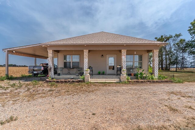 rear view of property featuring covered porch and a carport