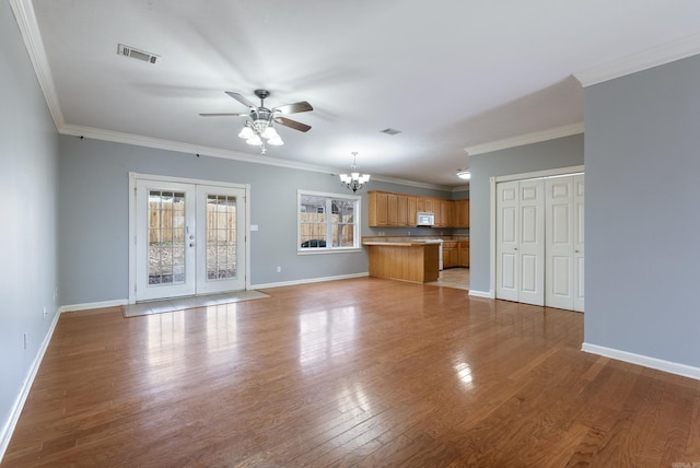 unfurnished living room featuring ceiling fan with notable chandelier, light wood-type flooring, crown molding, and french doors