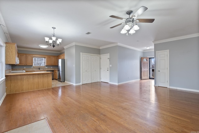 unfurnished living room with crown molding, sink, light hardwood / wood-style floors, and ceiling fan with notable chandelier