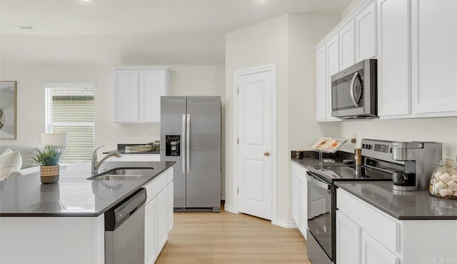 kitchen with sink, an island with sink, light hardwood / wood-style floors, white cabinetry, and stainless steel appliances