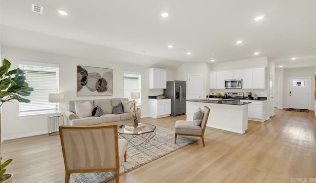 living room featuring lofted ceiling and light hardwood / wood-style flooring