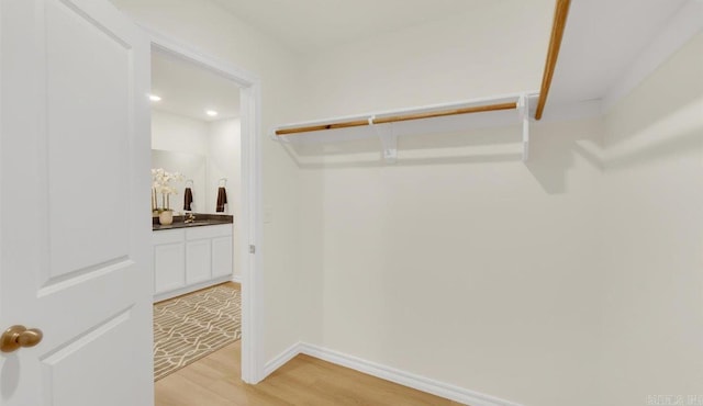 walk in closet featuring sink and light hardwood / wood-style floors