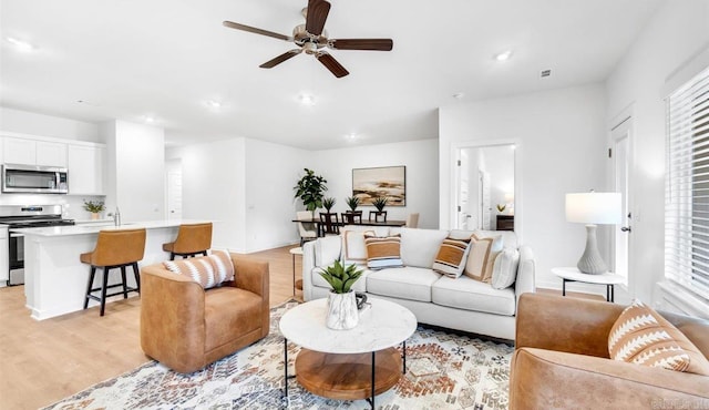 living room with light wood-type flooring and ceiling fan