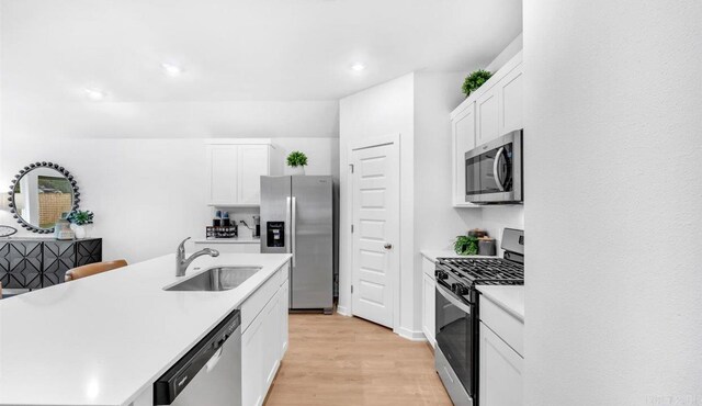 kitchen featuring stainless steel appliances, a kitchen island with sink, sink, light hardwood / wood-style flooring, and white cabinets