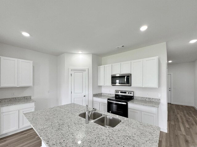 kitchen with wood finished floors, visible vents, a sink, white cabinets, and appliances with stainless steel finishes