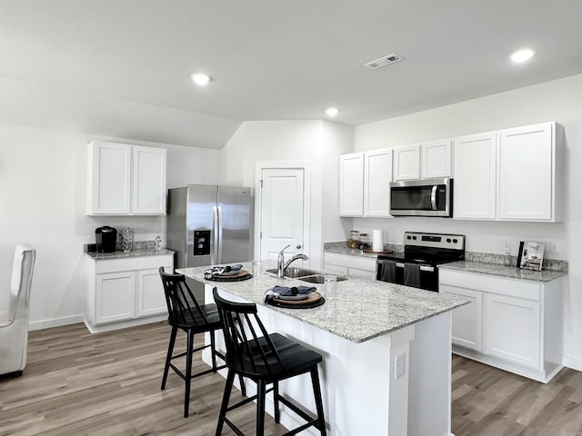 kitchen with white cabinetry, a kitchen island with sink, a kitchen bar, and stainless steel appliances