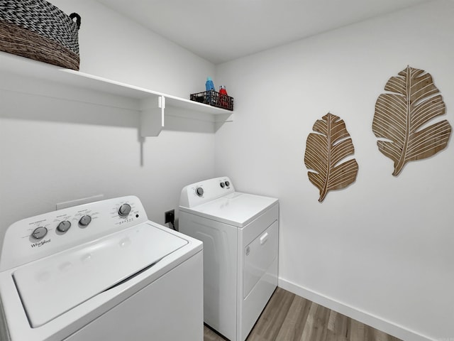 clothes washing area featuring washer and clothes dryer and hardwood / wood-style flooring