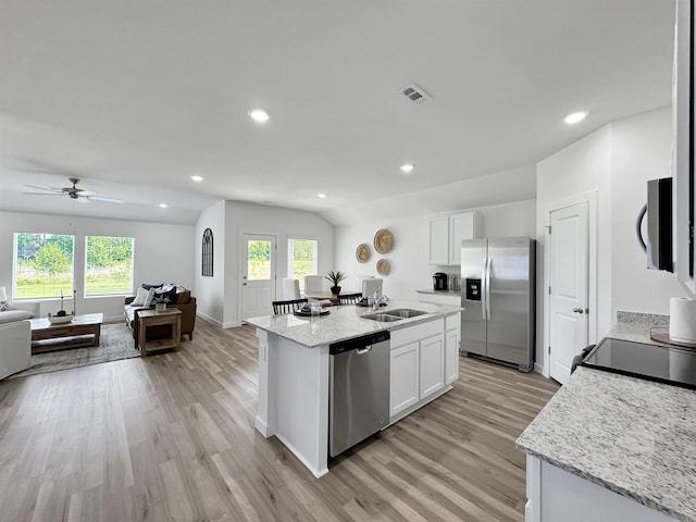 kitchen featuring a center island with sink, white cabinets, vaulted ceiling, and appliances with stainless steel finishes