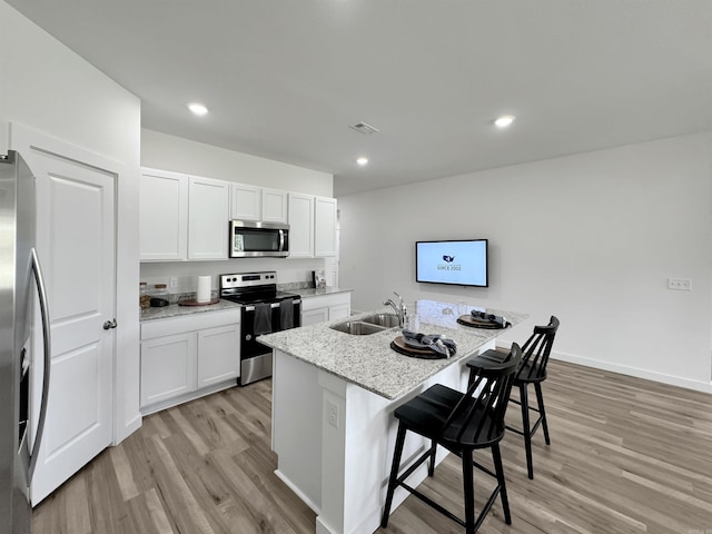 kitchen with a center island with sink, white cabinetry, sink, and appliances with stainless steel finishes