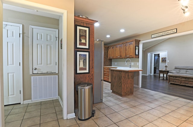 kitchen with a kitchen bar, kitchen peninsula, stainless steel refrigerator, and light tile patterned floors