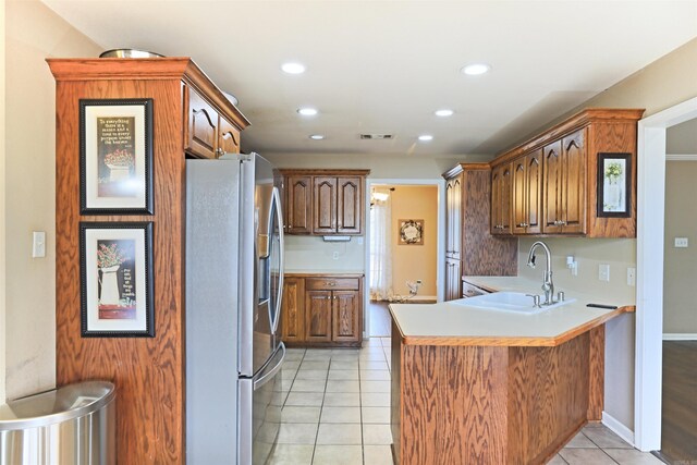 kitchen with kitchen peninsula, stainless steel fridge with ice dispenser, sink, and light tile patterned flooring