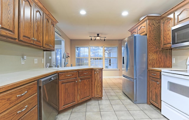 kitchen featuring light tile patterned floors, kitchen peninsula, sink, and appliances with stainless steel finishes