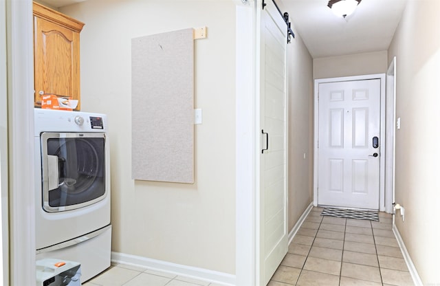 laundry area with cabinets, washer / dryer, a barn door, and light tile patterned floors