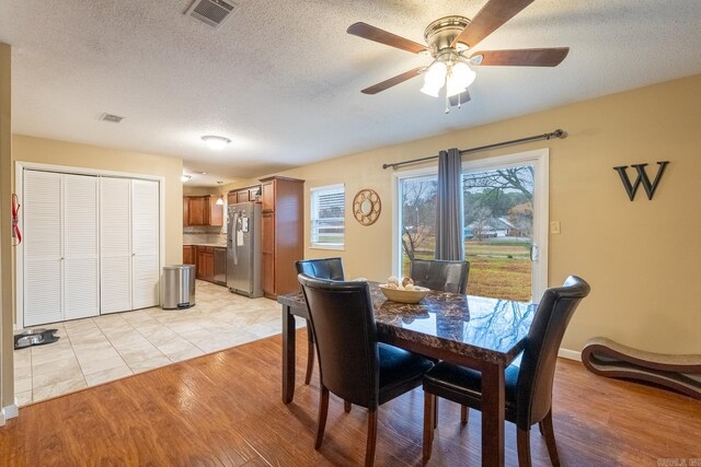 dining room with ceiling fan, light hardwood / wood-style floors, and a textured ceiling