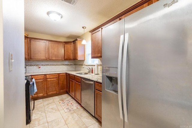 kitchen featuring decorative backsplash, light stone counters, stainless steel appliances, sink, and hanging light fixtures